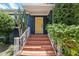 Inviting front entrance showcasing a bright yellow door, red tiled steps, and lush greenery at 2819 N Central Ave, Tampa, FL 33602