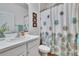 Bright bathroom features a shower with a decorative curtain, white vanity, and framed wall art at 2823 Holly Bluff Ct, Plant City, FL 33566