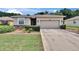 Inviting single-story home featuring a two-car garage, manicured lawn, and charming front garden at 2823 Holly Bluff Ct, Plant City, FL 33566