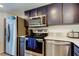 Modern kitchen features stainless steel appliances and dark upper and blue lower cabinets at 318 Windrush Blvd # 10, Indian Rocks Beach, FL 33785