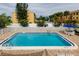 Community pool surrounded by a white fence, lush trees, and lounge seating at 318 Windrush Blvd # 10, Indian Rocks Beach, FL 33785