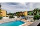 Community pool area with lounge chairs, tables, a white fence, and sunny landscaping at 318 Windrush Blvd # 10, Indian Rocks Beach, FL 33785