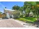 Charming home featuring lush landscaping, a brick driveway, and a quaint front porch with an American flag at 3220 W San Pedro St, Tampa, FL 33629