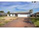 Charming single-story home with a metal roof, attached garage, brick driveway, and tropical landscaping in a sunny setting at 3290 Sunset N Dr, St Petersburg, FL 33710