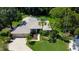 Aerial view of a pristine home featuring lush landscaping and sparkling blue pool at 3353 Wedgewood Way, Tarpon Springs, FL 34688