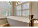Freestanding tub under arched windows featuring modern bronze faucet and white blinds for privacy at 3353 Wedgewood Way, Tarpon Springs, FL 34688