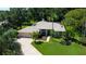 Inviting single-story home featuring a lush lawn, mature palm trees, and a convenient circular driveway at 3353 Wedgewood Way, Tarpon Springs, FL 34688