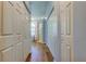 Hallway leading to bathroom with wood floors and storage closets on either side at 3353 Wedgewood Way, Tarpon Springs, FL 34688