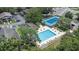 Aerial view of community pool, tennis court, parking lot, and apartments in lush green community at 4014 Dream Oak Pl # 202, Tampa, FL 33613