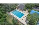 A community swimming pool surrounded by green lawn chairs and lush green trees at 4014 Dream Oak Pl # 202, Tampa, FL 33613