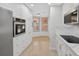 Well-lit kitchen featuring white cabinets, stainless steel appliances, marble countertops, and tile floors at 5430 Eagles Point Cir # 202, Sarasota, FL 34231
