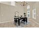 Elegant dining area featuring modern black table and chairs, chandelier, and abundant natural light from shuttered windows at 6439 Gentle Ben Cir, Wesley Chapel, FL 33544