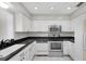 Well-equipped kitchen featuring stainless steel appliances, white cabinetry, and a sleek black countertop for cooking at 8451 Candlewood Rd # 8451, Seminole, FL 33777