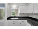 Functional kitchen area with white cabinets, black countertop, and modern fixtures, blending style and practicality at 8451 Candlewood Rd # 8451, Seminole, FL 33777