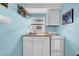 This kitchenette features blue walls, white cabinets, a stove and lots of natural light at 8537 93Rd Ave, Seminole, FL 33777