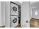 This laundry room features a stacked washer and dryer, a white door and wood-look floors at 8537 93Rd Ave, Seminole, FL 33777