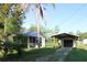 View of screened in porch, garage and separate car port in backyard setting with grass and trees at 8807 Mary Ivy Dr, Plant City, FL 33567