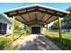 Carport framing the detached garage and driveway amidst a lush green lawn at 8807 Mary Ivy Dr, Plant City, FL 33567