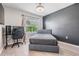 This bedroom features a neutral palette, streamlined furniture, and bright natural light from a window overlooking the lawn at 9028 Forge Breeze Loop, Wesley Chapel, FL 33545