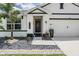 Close up of a beautifully landscaped front porch with decorative black front door, and rock garden at 9028 Forge Breeze Loop, Wesley Chapel, FL 33545