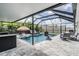 Screened in pool with sun umbrella, basketball hoop, in pool loungers, and outdoor kitchen at 9028 Forge Breeze Loop, Wesley Chapel, FL 33545