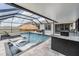 Screened-in pool with in-pool lounger, outdoor kitchen, bar and dining at 9028 Forge Breeze Loop, Wesley Chapel, FL 33545