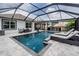Resort-style screened-in pool with sun loungers, seating area, and outdoor kitchen at 9028 Forge Breeze Loop, Wesley Chapel, FL 33545