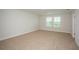 A spacious bedroom with neutral colored carpet and a view from the double windows at 10036 Surrey Rose Dr, San Antonio, FL 33576