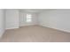 A spacious bedroom with neutral colored carpet and a view from the double windows at 10036 Surrey Rose Dr, San Antonio, FL 33576