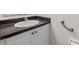 Close up of bathroom vanity with dark countertops and white cabinets and fixtures with chrome faucet and grab bar on the side at 1050 Starkey Rd # 704, Largo, FL 33771