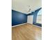Well-lit bedroom with blue accent wall, hardwood floors, a ceiling fan, and a window with blinds at 1050 Starkey Rd # 704, Largo, FL 33771