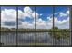 Screened balcony overlooking a tranquil lake with views of neighboring buildings and a clear blue sky filled with fluffy clouds at 10520 Boardwalk Loop # 202, Bradenton, FL 34202