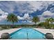 Resort-style community pool with inviting lounge chairs and swaying palm trees under a sunny, cloudy sky at 10520 Boardwalk Loop # 202, Bradenton, FL 34202