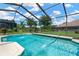Sparkling pool inside screened enclosure with a view of the yard and a pond at 11153 Biddeford Pl, New Port Richey, FL 34654