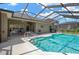 Sparkling pool inside screened enclosure surrounded by patio, grill, and seating at 11153 Biddeford Pl, New Port Richey, FL 34654