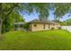 Large backyard with lush green lawn, mature trees, and a screened-in patio area at 12031 Mountbatten Dr, Tampa, FL 33626