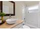 Bright bathroom featuring a vessel sink, wood-framed mirror, and tiled shower-tub combo with natural light at 12031 Mountbatten Dr, Tampa, FL 33626