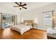 Comfortable bedroom with hardwood floors, a ceiling fan, slider to the pool area and natural light at 12031 Mountbatten Dr, Tampa, FL 33626