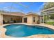 Backyard pool with brick deck, covered patio, and desert-toned exterior of house at 12031 Mountbatten Dr, Tampa, FL 33626