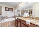 Bathroom boasts double sink vanity, tiled tub, framed mirror and ample lighting at 13194 Royal Pines Ave, Riverview, FL 33579