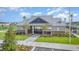 Front exterior of clubhouse, featuring a covered entrance, mature trees and manicured landscaping at 13194 Royal Pines Ave, Riverview, FL 33579