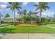 Front view of the community clubhouse with palm trees, bright green lawn and colorful flowerbeds at 13194 Royal Pines Ave, Riverview, FL 33579
