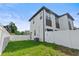 The modern two-story home has a fenced backyard featuring fresh green grass and a bright white privacy fence at 1500 49Th N St, St Petersburg, FL 33710