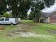 View of a single-story home with brown trim, a garage, and a large yard with grass and trees at 17004 State Road 54, Lutz, FL 33558