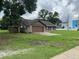 A single-story home with brown trim sits on a spacious lot with ample green space, near a sidewalk at 17004 State Road 54, Lutz, FL 33558
