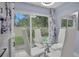 The dining area includes white chairs, a glass table, curtains, and sliding glass doors leading to the backyard at 1701 Pinehurst Rd # 33E, Dunedin, FL 34698
