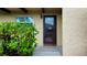 Welcoming front door featuring a glass storm door, small welcome home sign, and a small garden at 1701 Pinehurst Rd # 33E, Dunedin, FL 34698