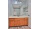 Bathroom with wooden vanity, large mirror, and walk-in shower with white tiles and glass doors at 1717 Atrium Dr, Sun City Center, FL 33573