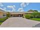 Home's exterior features well-maintained landscaping, a carport, and colorful plantings at 1717 Atrium Dr, Sun City Center, FL 33573