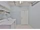 Bright laundry room with white washer and dryer, shelving and a white door at 1717 Atrium Dr, Sun City Center, FL 33573
